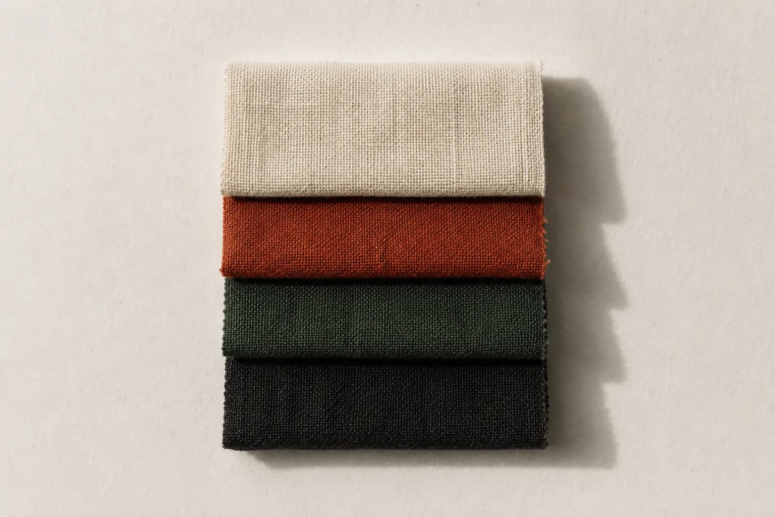 Four fabric swatches stacked with aligned edges on archival paper.
